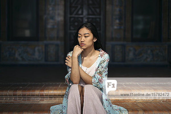 Porträt einer schönen jungen Frau  die auf einer Treppe sitzt und einen Kimono trägt