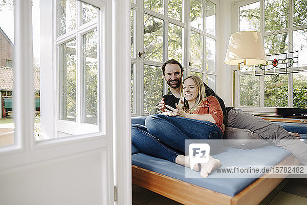 Happy couple relaxing on couch  using smartphone