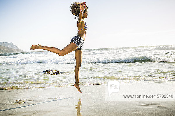 Glückliche junge Frau springt am Strand