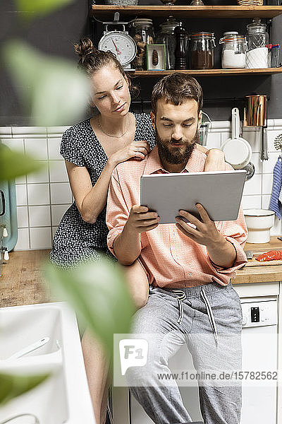 Junges Paar benutzt digitales Tablett in der Küche