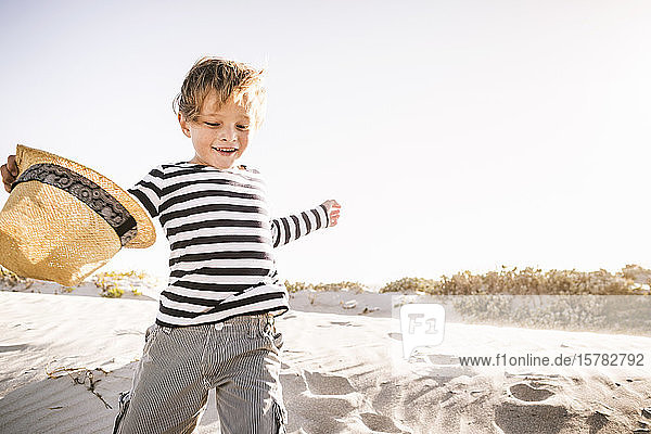 Happy boy with hat running on the beach