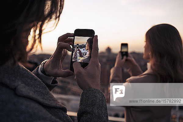 Junges Paar beim Fotografieren mit dem Handy auf einem Balkon über der Stadt Venedig  Italien