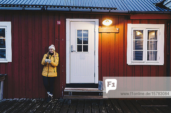Tourist mit Smartphone in einer Hütte in Hamnoy Lofoten Norwegen