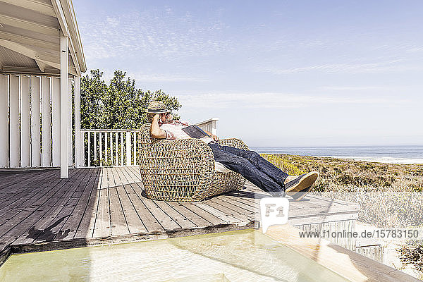 Mann schlief beim Lesen eines Buches auf einem Deck an der Küste ein