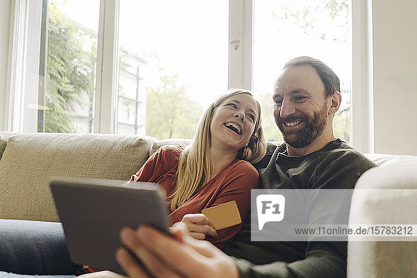 Couple sitting at home on couch  using digital tablet