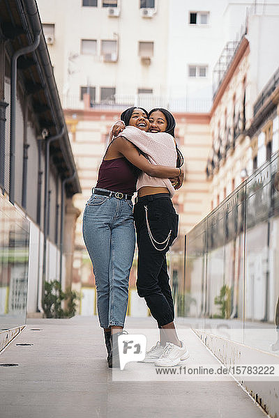 Zwei glückliche junge Frauen umarmen sich in der Stadt