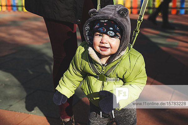 Porträt eines glücklichen kleinen Jungen auf dem Spielplatz an einem sonnigen Wintertag