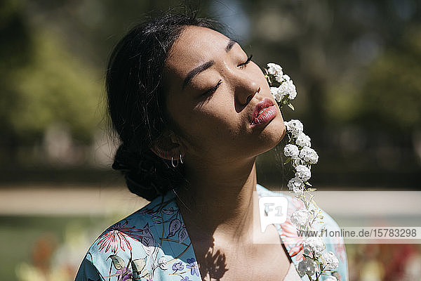 Schöne junge Frau mit Blume in einem öffentlichen Garten im Frühling