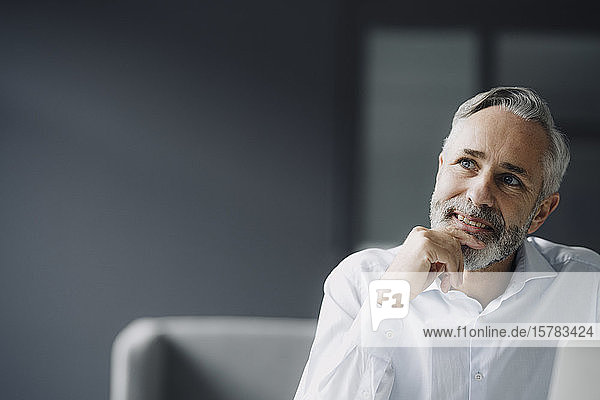 Portrait of pensive mature businessman in his office looking at distance