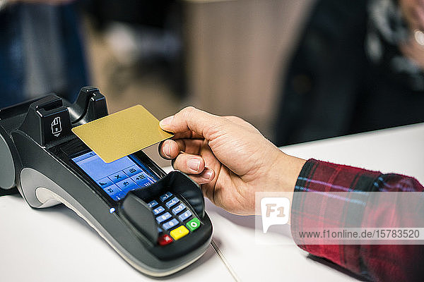 Nahaufnahme eines kontaktlos mit Kreditkarte zahlenden Mannes