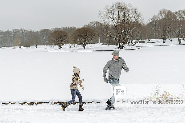 Father and daughter running in winter landscape