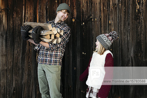 Glückliche Vater und Tochter halten im Winter Brennholz