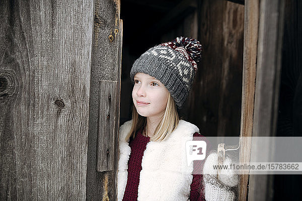 Mädchen mit Wollmütze an Holztür