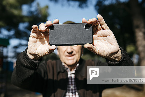 Old man taking pictutes with his smartphone