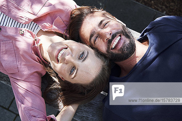 Porträt eines glücklichen Paares  das Kopf an Kopf auf einer Bank liegt