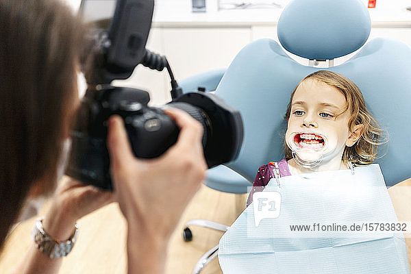Dentist taking picture of girl receiving dental treatment