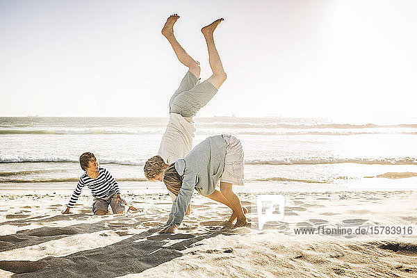 Vater amüsiert sich mit seinem Sohn am Strand  übt