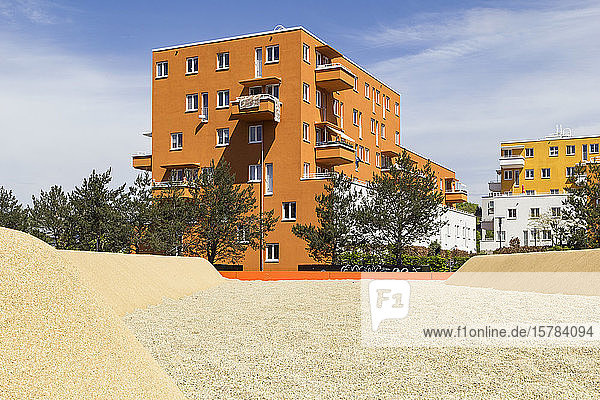 Deutschland  Bayern  München  Sandfarbener Spielplatz vor orange gestrichenem Wohngebäude