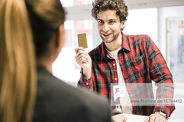 Mann  der mit Kreditkarte an der Ladentheke eines Geschäfts bezahlt