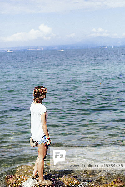 Junge Frau steht am Seeufer  Gardasee  Italien