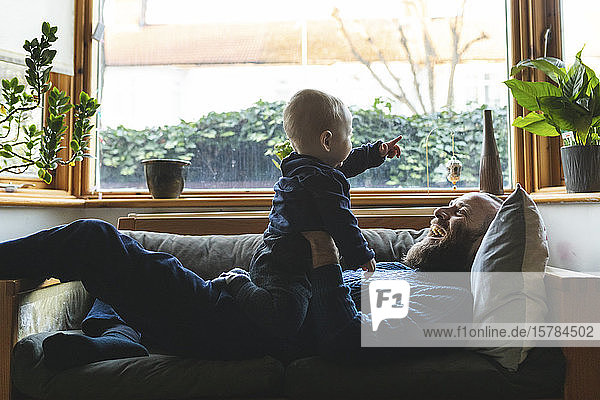 Mann spielt mit seinem kleinen Sohn auf dem Sofa