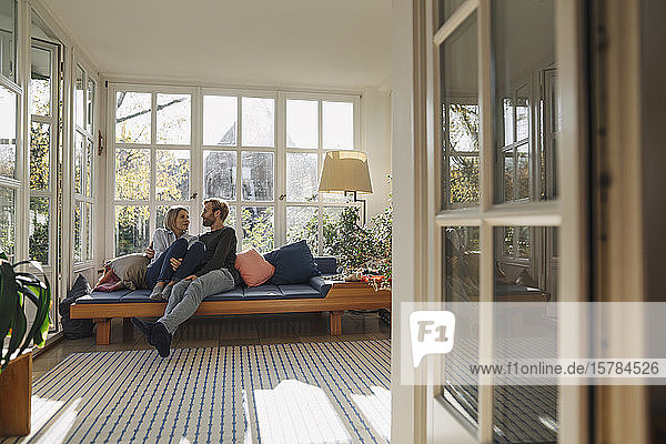 Affectionate couple relaxing in sunroom at home