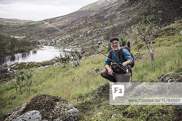 Laughing fly fisherman at river bank with mountains  Lakselv  Norway