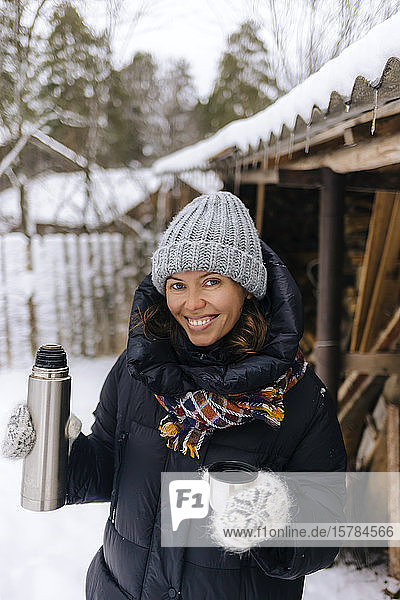 Portrait of happy woman with thermo flask in winter