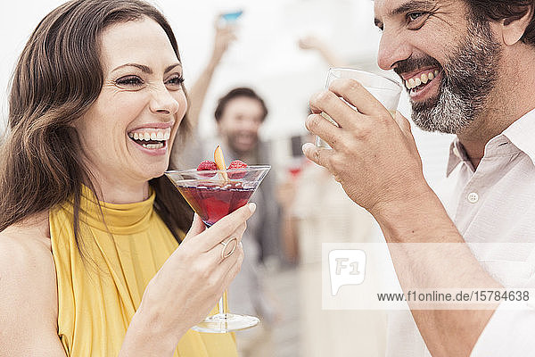 Glückliches Paar und Freunde beim geselligen Beisammensein auf einer Cocktailparty