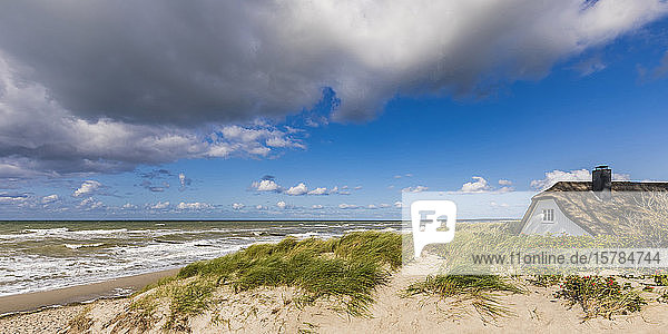 Deutschland  Mecklenburg-Vorpommern  Ahrenshoop  Wolken über strohgedecktem Haus am Sandstrand der Ostsee