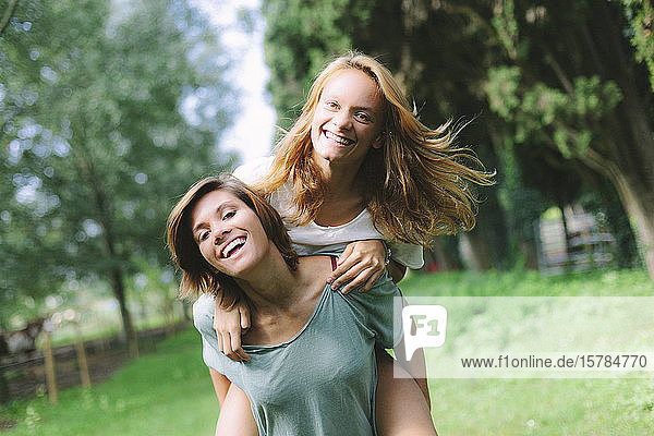 Porträt einer glücklichen jungen Frau  die ihren Freund huckepack trägt
