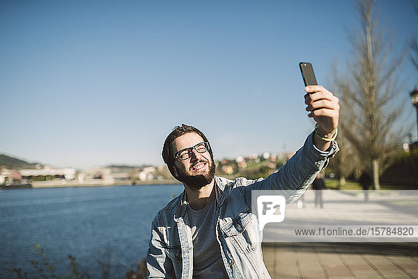 Junger Mann nimmt Smartphone-Selbstfahrer am Meer