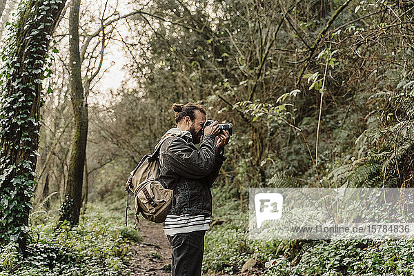 Junger Mann fotografiert im Wald mit seiner Kamera