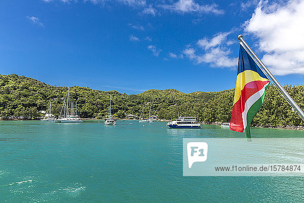 Seychellen  Insel Praslin  Flagge der Seychellen mit Yachthafen im Hintergrund
