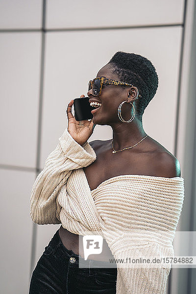 Portrait of laughing young woman on the phone wearing sunglasses