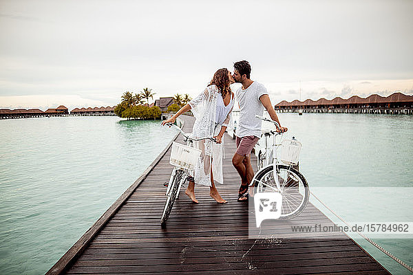 Couple with bicycles kissing on a jetty in the sea  Maguhdhuvaa Island  Gaafu Dhaalu Atoll  Maldives