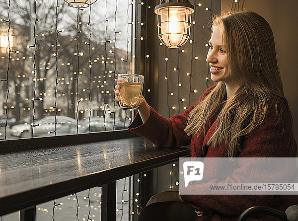 Lächelnde junge Frau mit einer Tasse Tee in einem Café