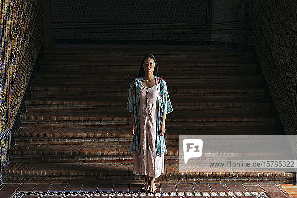 Porträt einer schönen jungen Frau in einem Kimono  die an einer Treppe steht