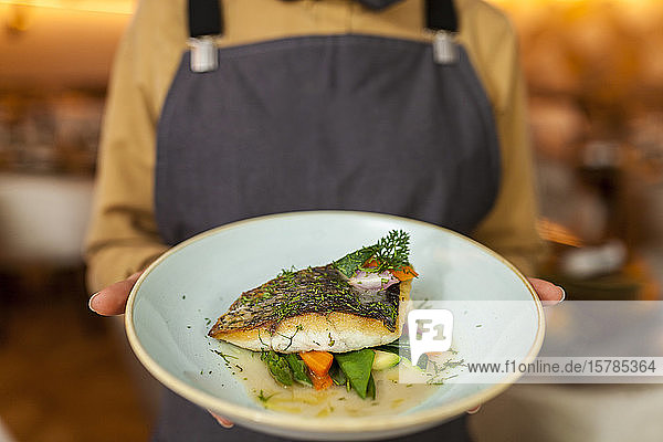 Kellnerin serviert gesunden Fisch und Gemüse