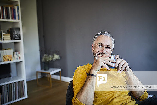 Porträt eines lächelnden entspannten reifen Mannes zu Hause bei einer Tasse Kaffee