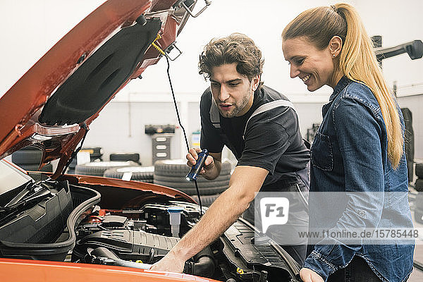 Car mechanic talking to client in workshop