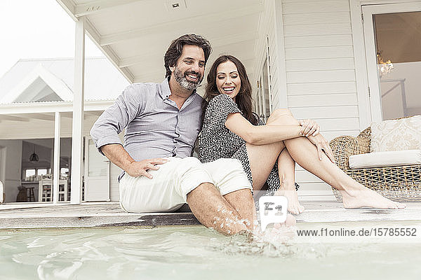 Glückliches Paar beim Entspannen am Pool eines Ferienhauses