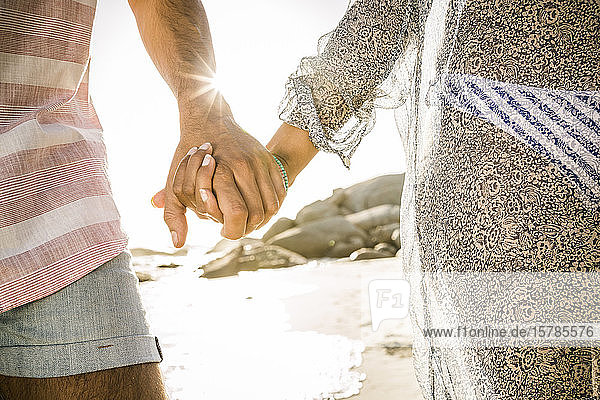 Nahaufnahme eines Paares  das sich am Strand an den Händen hält