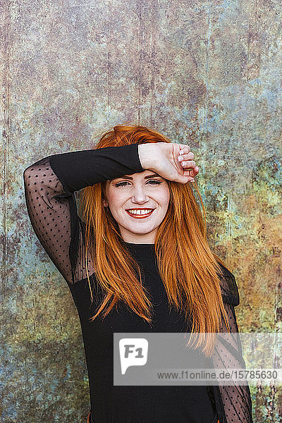 Porträt einer glücklichen rothaarigen jungen Frau in Schwarz gekleidet