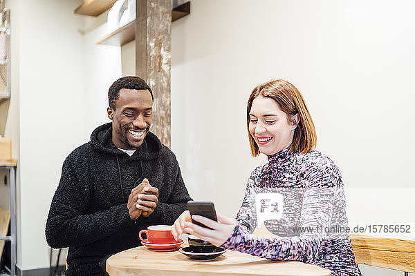 Smiling man and woman with cell phone in a cafe