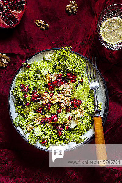 Schale mit grünem Salat mit Walnüssen und Granatapfelkernen