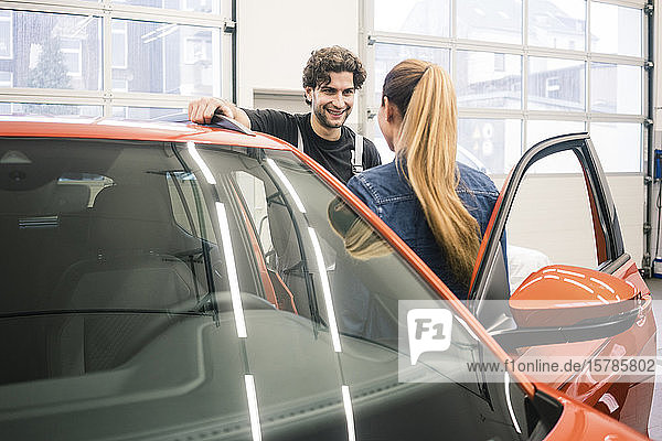 Automechaniker im Gespräch mit Kunden in der Werkstatt