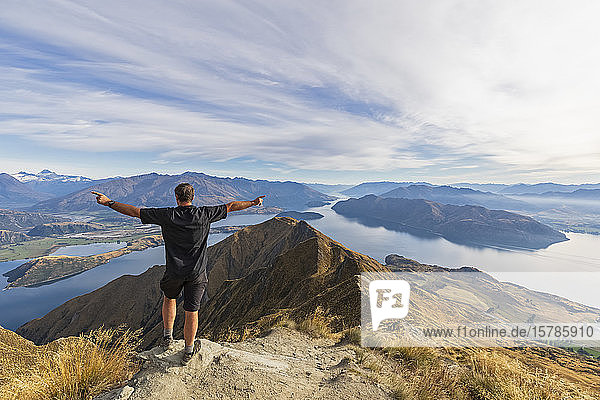 Hiker standing on viewpoint at Roys Peak  looking to Mount Aspiring  Lake Wanaka  South Island  New Zealand