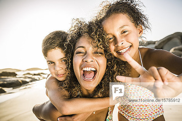 Porträt einer glücklichen Mutter mit ihren zwei Kindern  die sich am Strand amüsieren