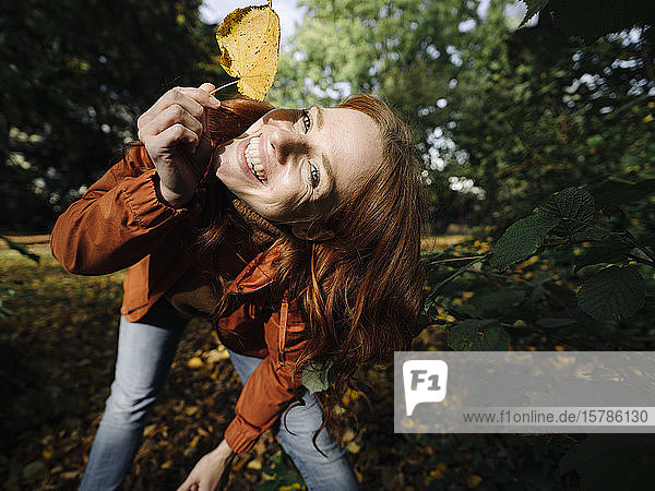 Porträt einer glücklichen rothaarigen Frau mit Herbstblatt